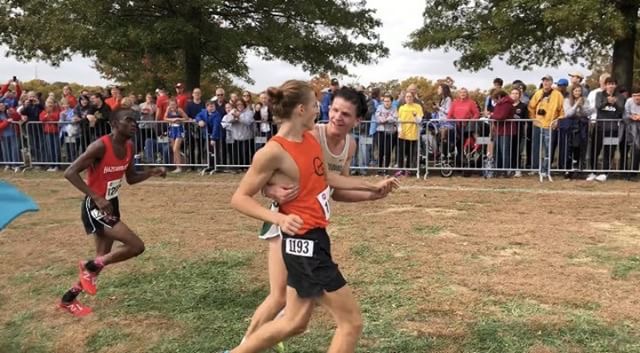 Connor Kingsland (12) helps fellow runner across the finish line.