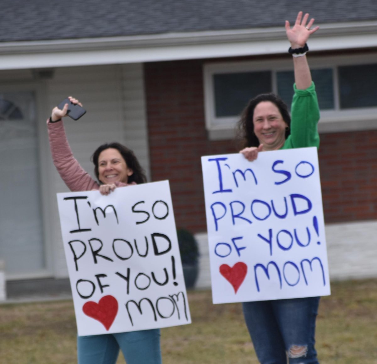 Two women, most likely the relatives of some protesters, hold up signs praising the walkout. Both signs say, "I'm so proud of you! Mom"